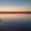 Orange and yellow colours on the horizon viewed across a sandy beach during a sunset . Location pictured is Broad Haven North, Pembrokeshire