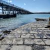 View from beneath a pier structure jutting out into a body of water with pipes running along one side of the structure. location is South Hook, Pembrokeshire