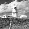 Black and white photograph of a lighthouse atop a grassy hill. Location photograph is Strumble Head