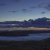 View of an island from the mainland at dusk. The twilight makes the grassy mainland and island seem almost purple in colour and sea a grey blue shade. Location pictured is Skomer Island from the Deer Park, Pembrokeshire