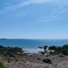 View from a rocky beach out to see, with four kayaks lying on the sandy area of the beach where the sea is lapping the shore. The sky is blue and sea is reflecting the sunny conditions. Location pictured is on the Dale Peninsula, Pembrokeshire